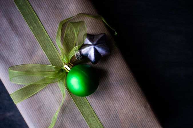 Top view of gift with green ribbon and Christmas ornaments