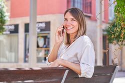 Cheerful woman having phone call on street