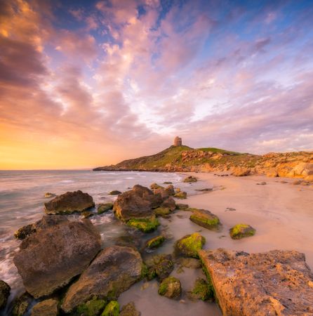 Gray rocks on seashore under sky during golden hour