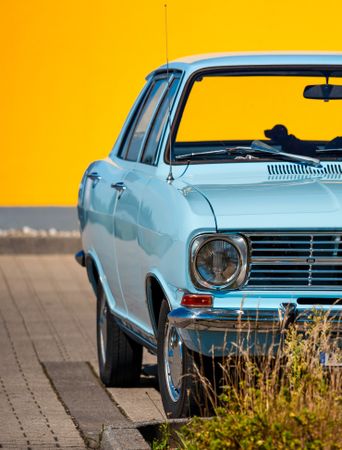 Sky blue retro car against a bright yellow wall. Color contrast.