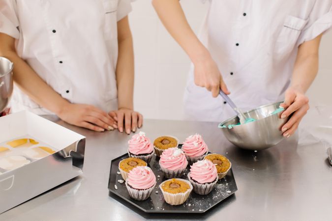 Two people preparing cupcake icing