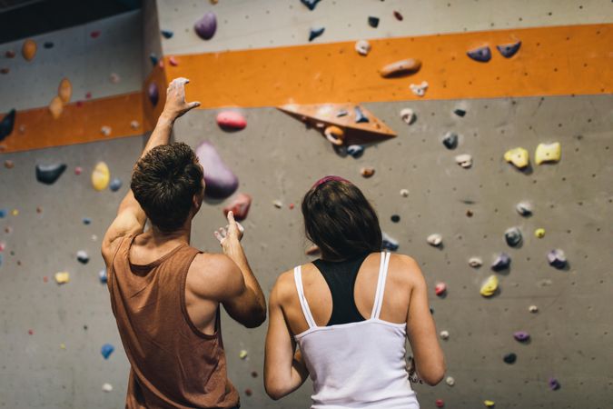 Skilled rock climber discussing rock climbing technique with female climber