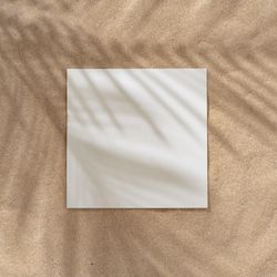 Sand with palm leaf shadows and central square