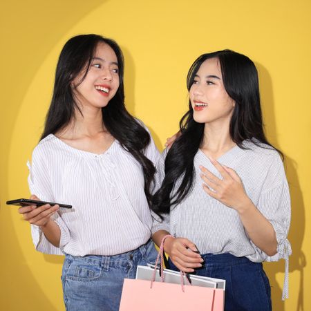 Two Young Woman Holding Shopping Bag with Attractive Smiling