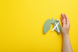 Lungs cut out of green paper with ribbon held by hand with copy space