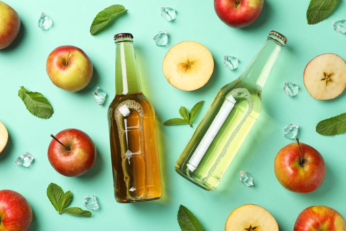 Composition with cider, apples and ice on mint background