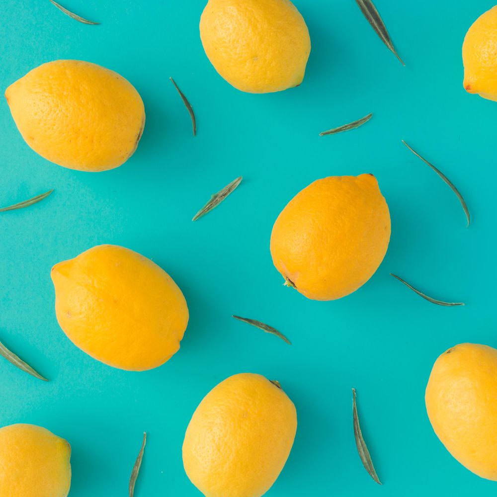 Lemons and green leaves on bright blue background