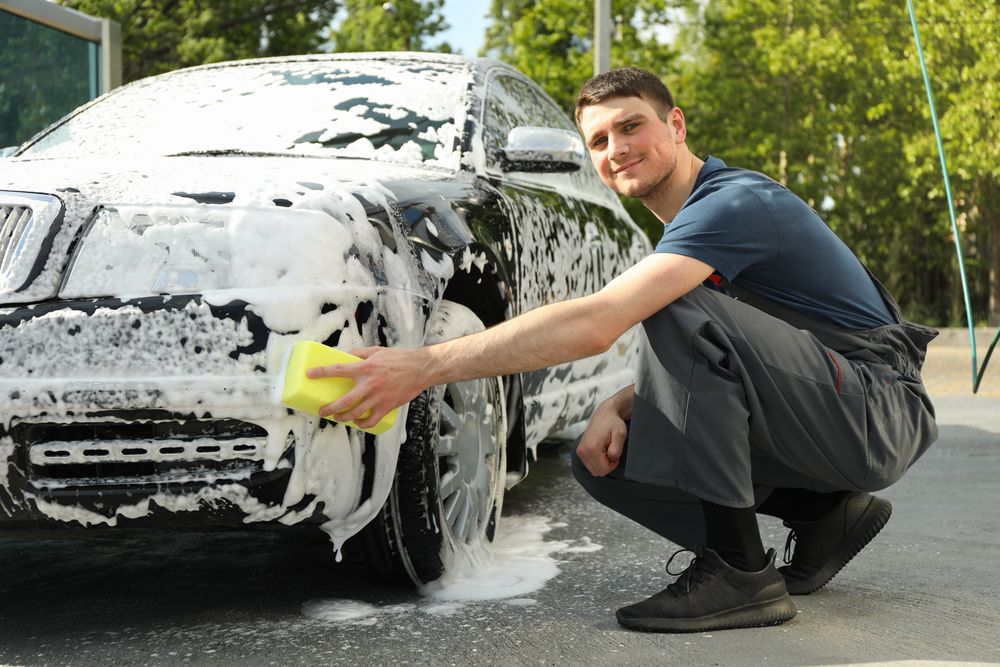 Man wipes the car with a sponge. Car wash. Clear car concept
