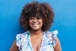 Black smiling woman with blue background.