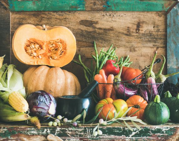 Seasonal fall vegetables, squash, carrots, tomatoes, against rustic wooden wall, copy space