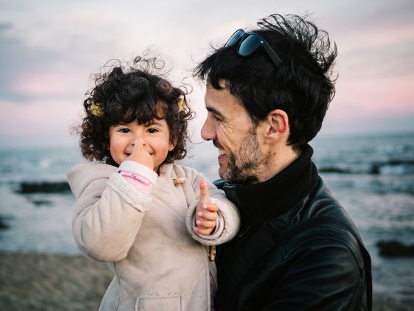 father holding little daughter at the beach