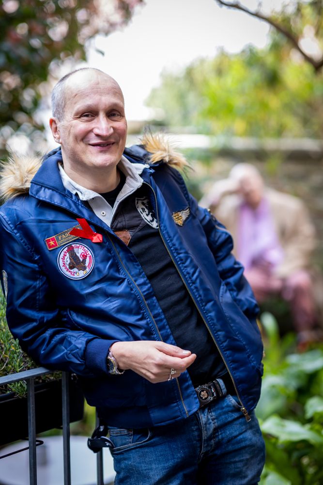 Smiling older man leaning on rail in blue jacket