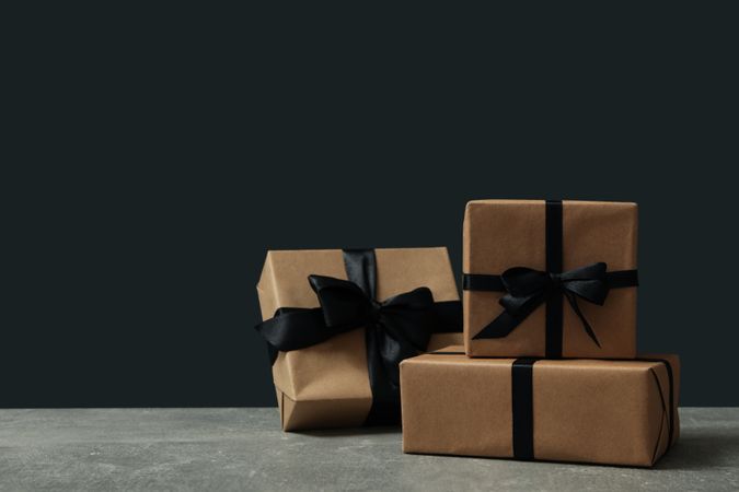 Craft gift boxes with bow on gray table against dark background
