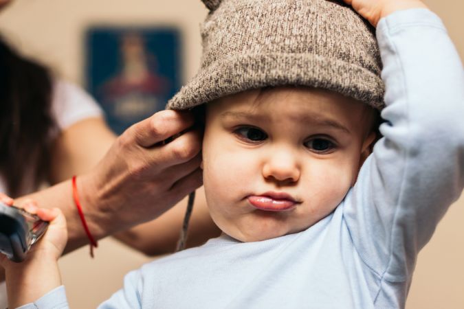 mother putting a hat on her baby at home