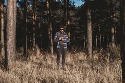 Confident photographer taking picture with camera in sunny forest