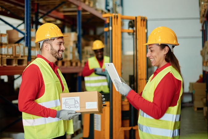 Warehouse Workers Smiling and Collaborating on Package Handling