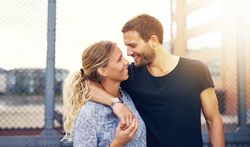 Couple smiling at each other with man’s arm around the woman’s shoulder