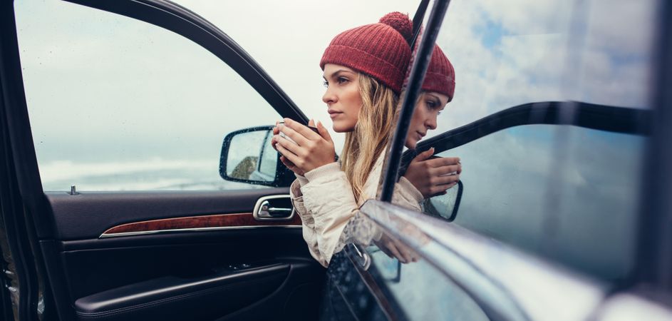 Female on road trip drinking coffee inside car