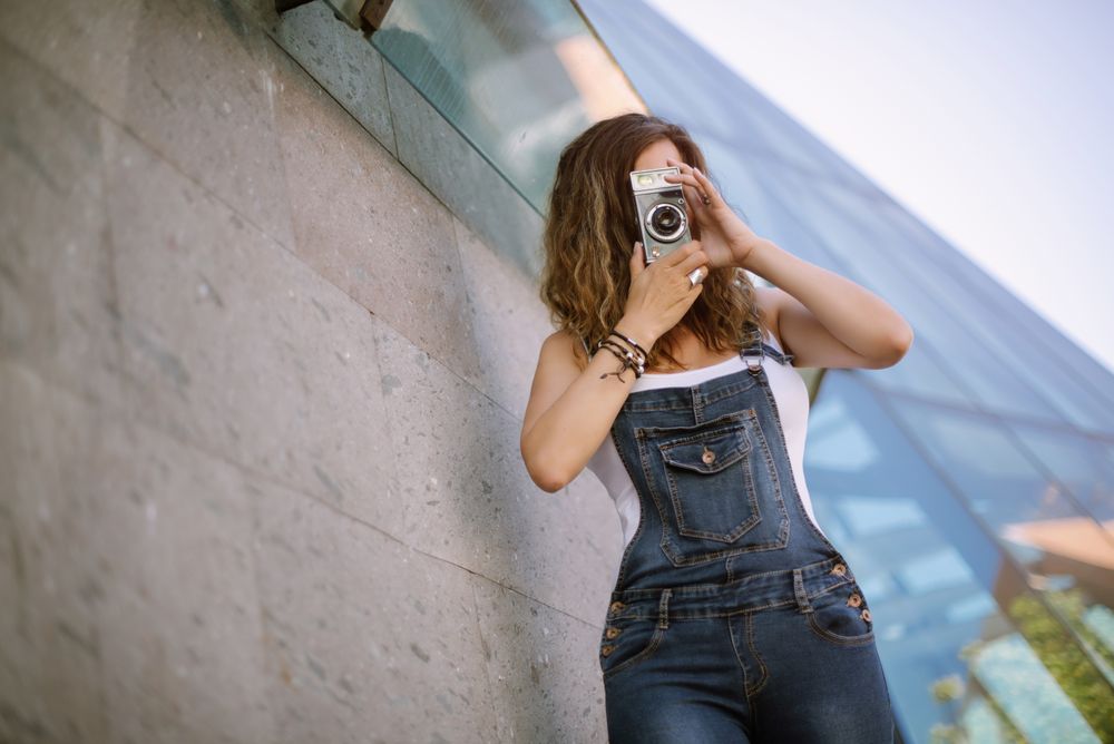 Creative woman taking photo on camera in sunny day