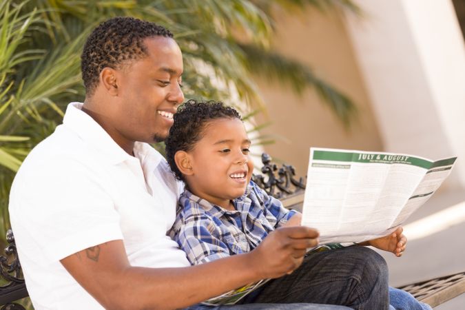 Black Father and Son Reading Park Brochure Outside