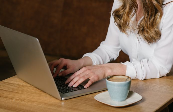 Anonymous young woman using laptop in cafe