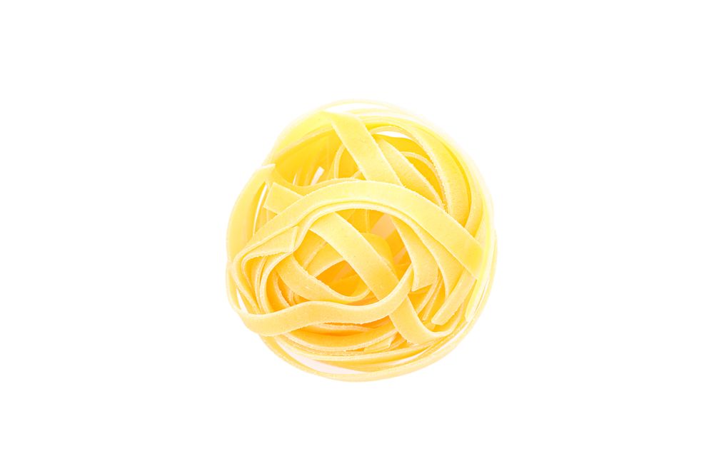 Pasta isolated on light background, top view. Traditional shape of dry uncooked whole pasta