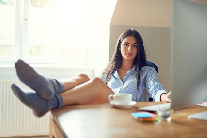 Arab woman sitting at her desk with feet up first thing in the morning