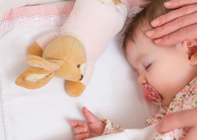 Hands of mother caressing her baby girl sleeping