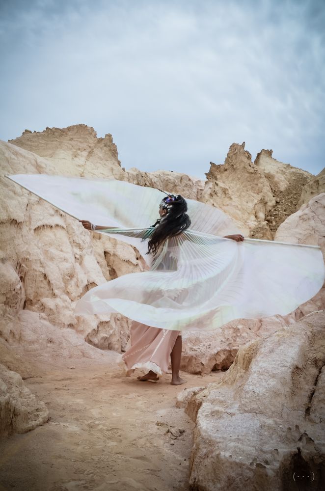 Woman in light outfit dancing between rocks