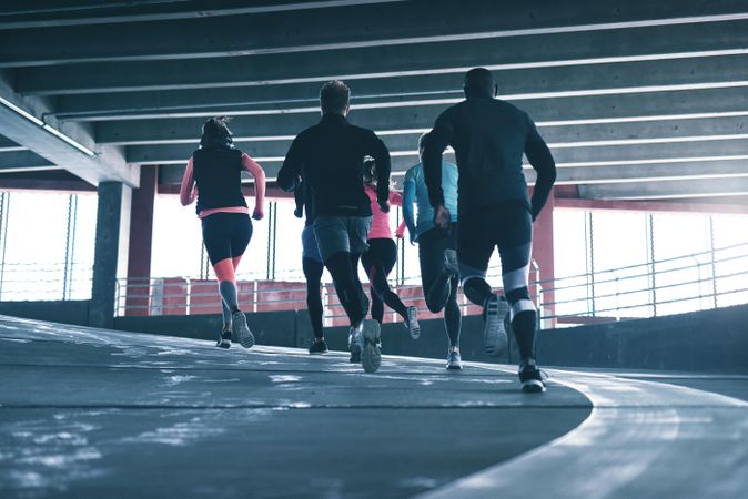 Rear view of people running up an ascent on a concrete track