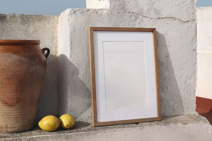 Vertical wooden frame mockup against old textured wall in sunlight with fresh yellow lemons