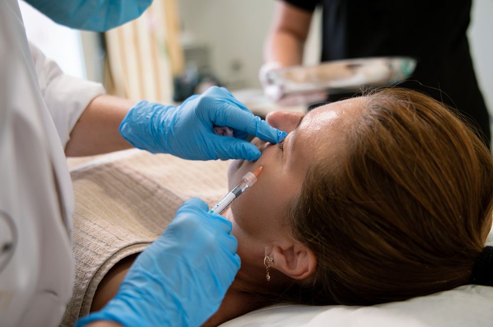 Anonymous beautician administering injection to cheek of female client