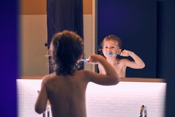 Boy brushing teeth in bathroom in morning