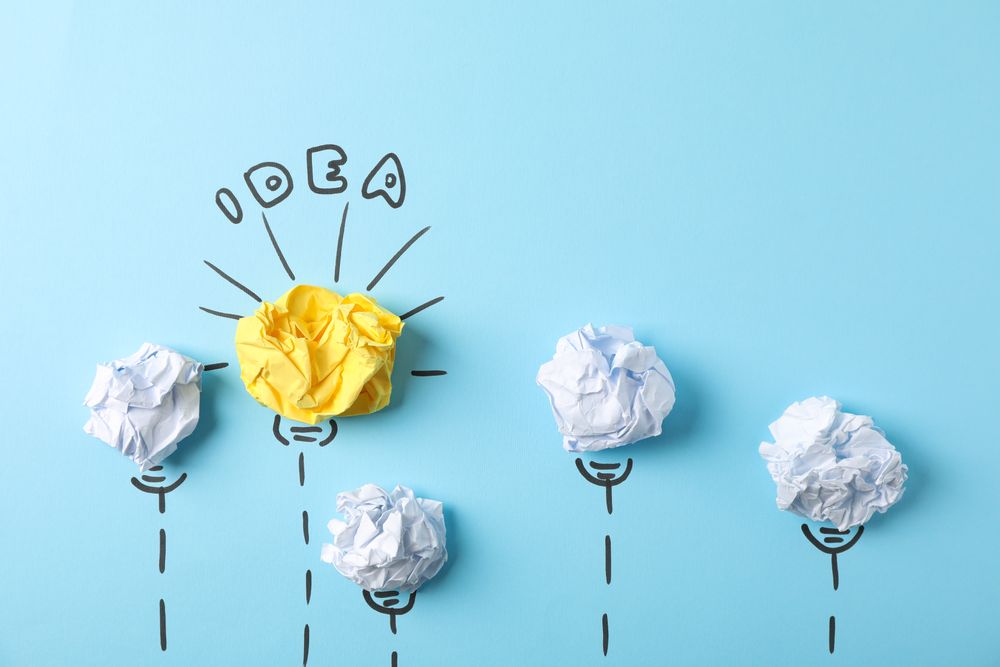 Light bulb and paper balls on blue background, space for text