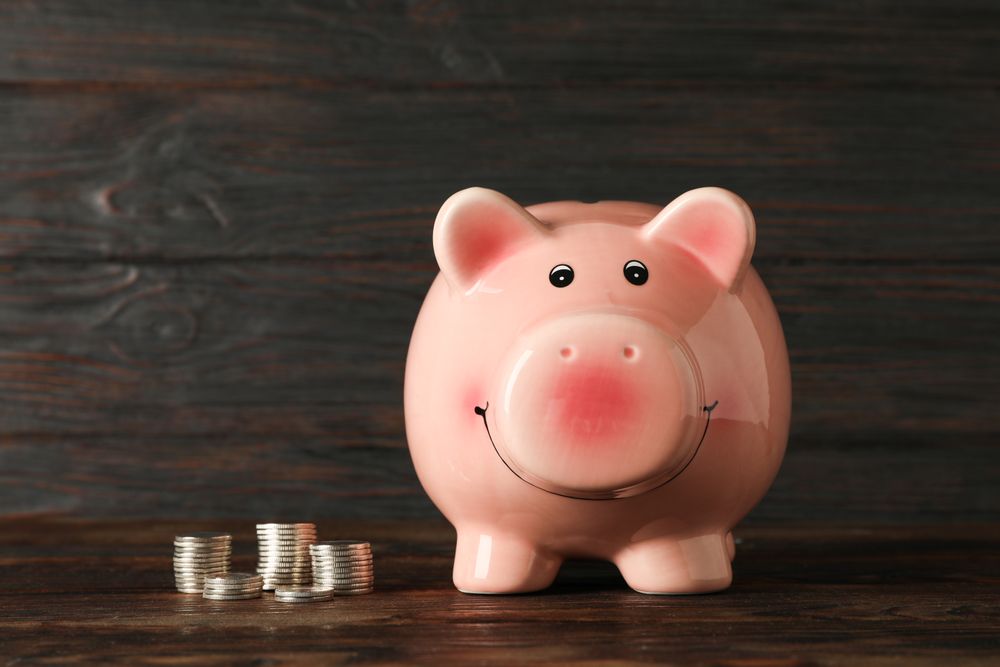 Happy piggy bank with money on wood table against wooden background, space for text. Finance, saving money