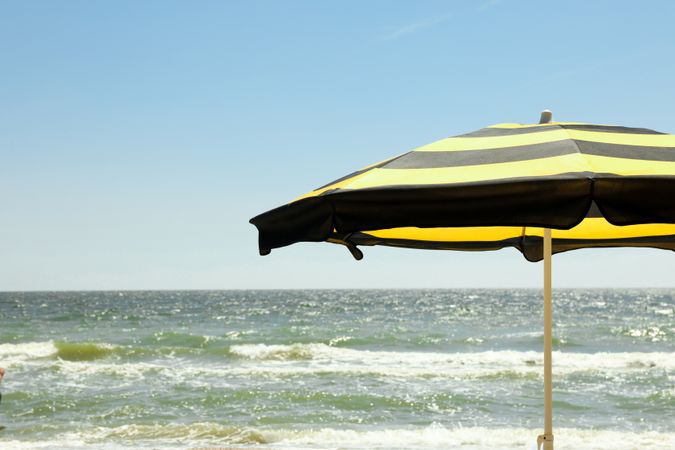 Striped yellow beach umbrella against blue sea