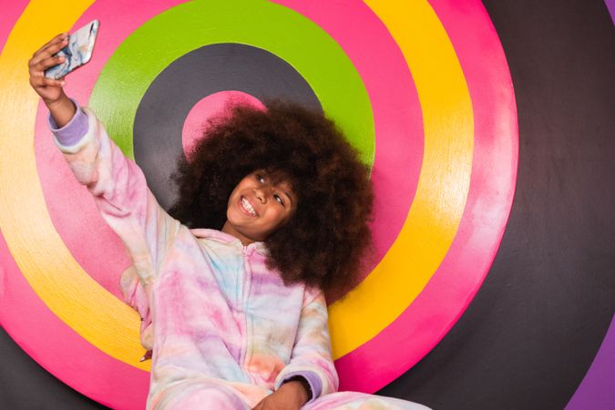 Smiling Black girl taking selfie in studio