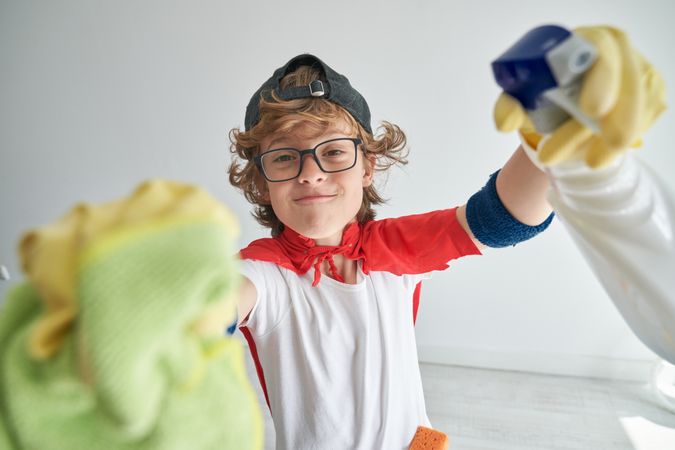 Content child in superhero costume wiping camera against white w