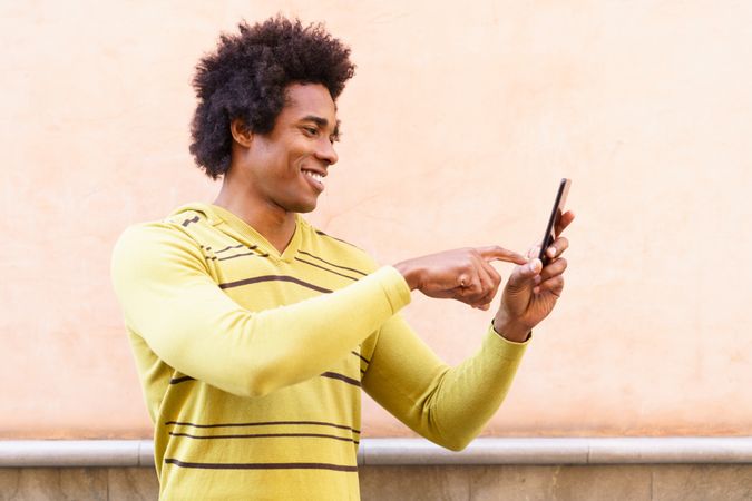 Man smiling at phone screen outside