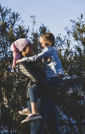 Woman with cancer head scarf holding girl