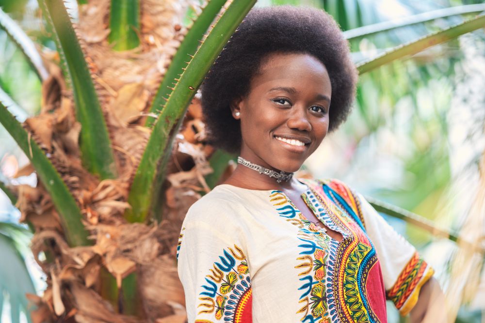 Cheerful Black woman  amidst palm leaves