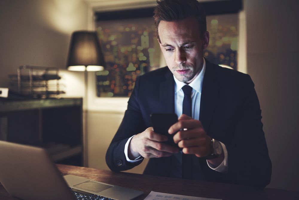 Businessman in suit texting at night