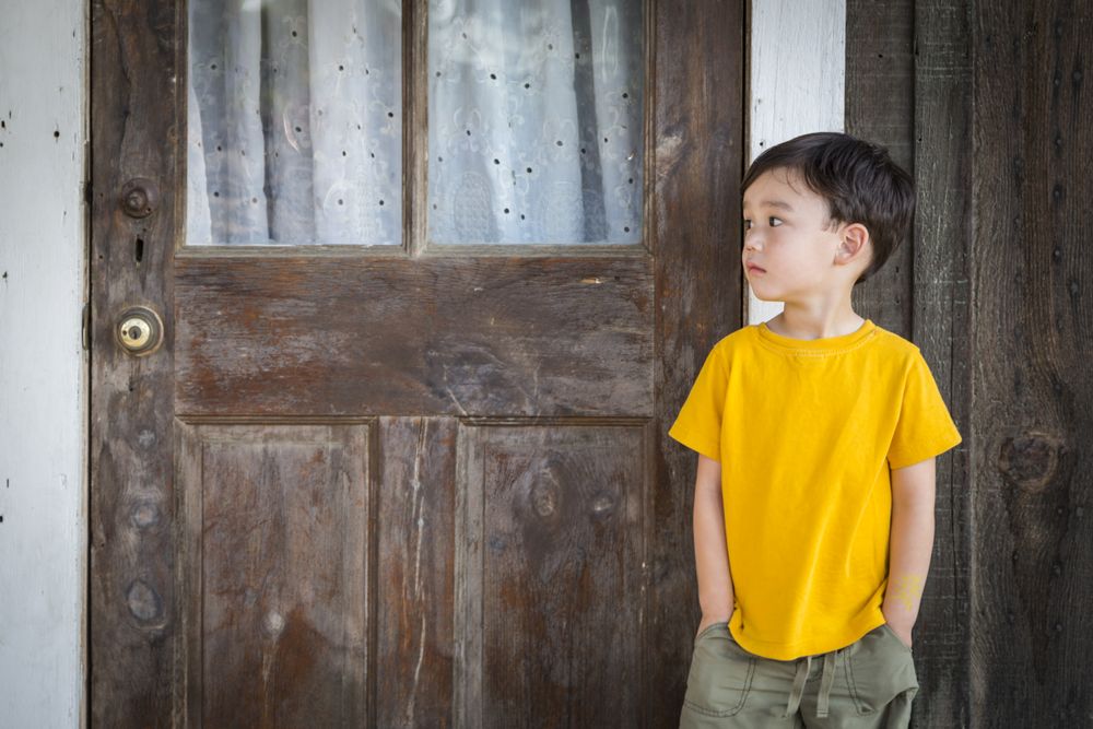 Melancholy Boy Standing In Front of Door