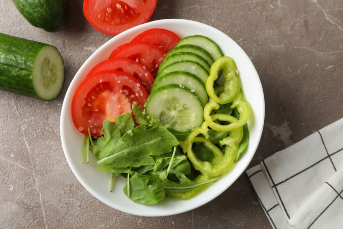 Plate with fresh vegetable slices on grey background, close up