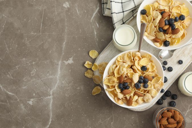 Concept of breakfast with muesli, berry, nut and milk on gray table