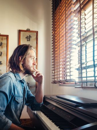 Thoughtful male playing synthesizer at home