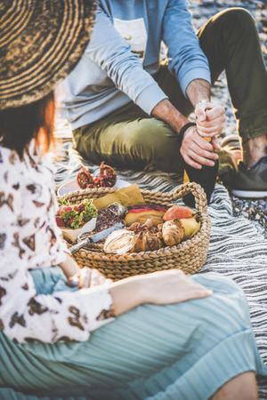 Two people at summer picnic as man opens wine