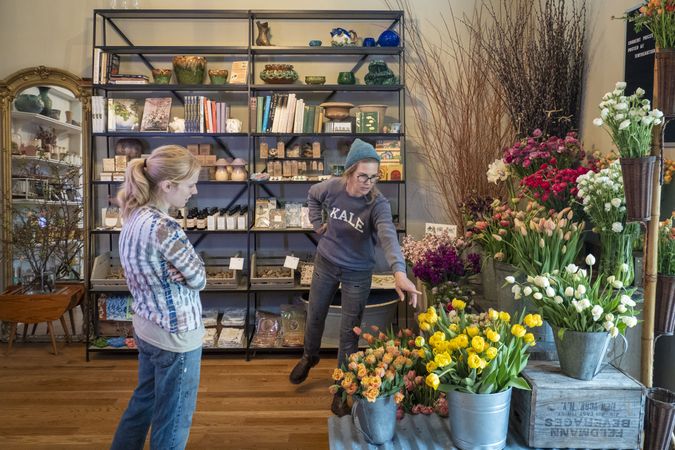 Copake, New York - May 19, 2022: Woman pointing at tulips in bucket in shop