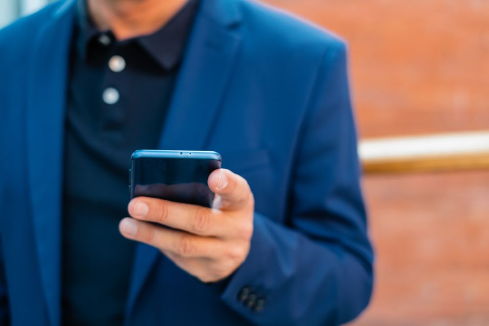 businessman in blue jacket using smartphone