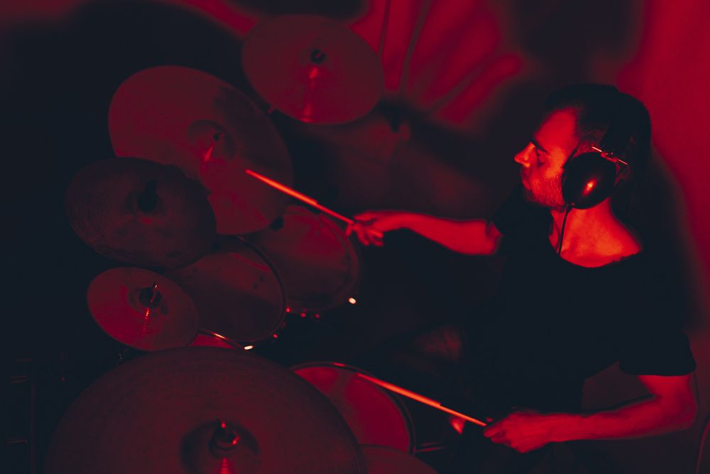 Man with drumsticks playing on drums in redness